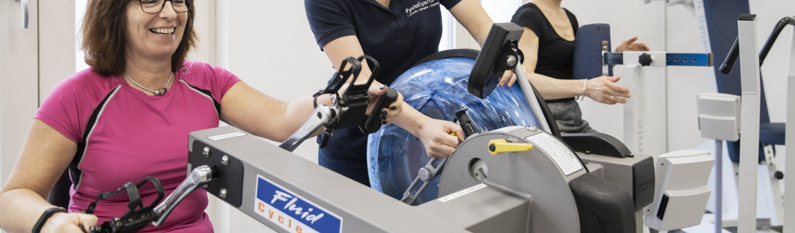 patiënt beweegt onder begeleiding van fysiotherapeut, handbike